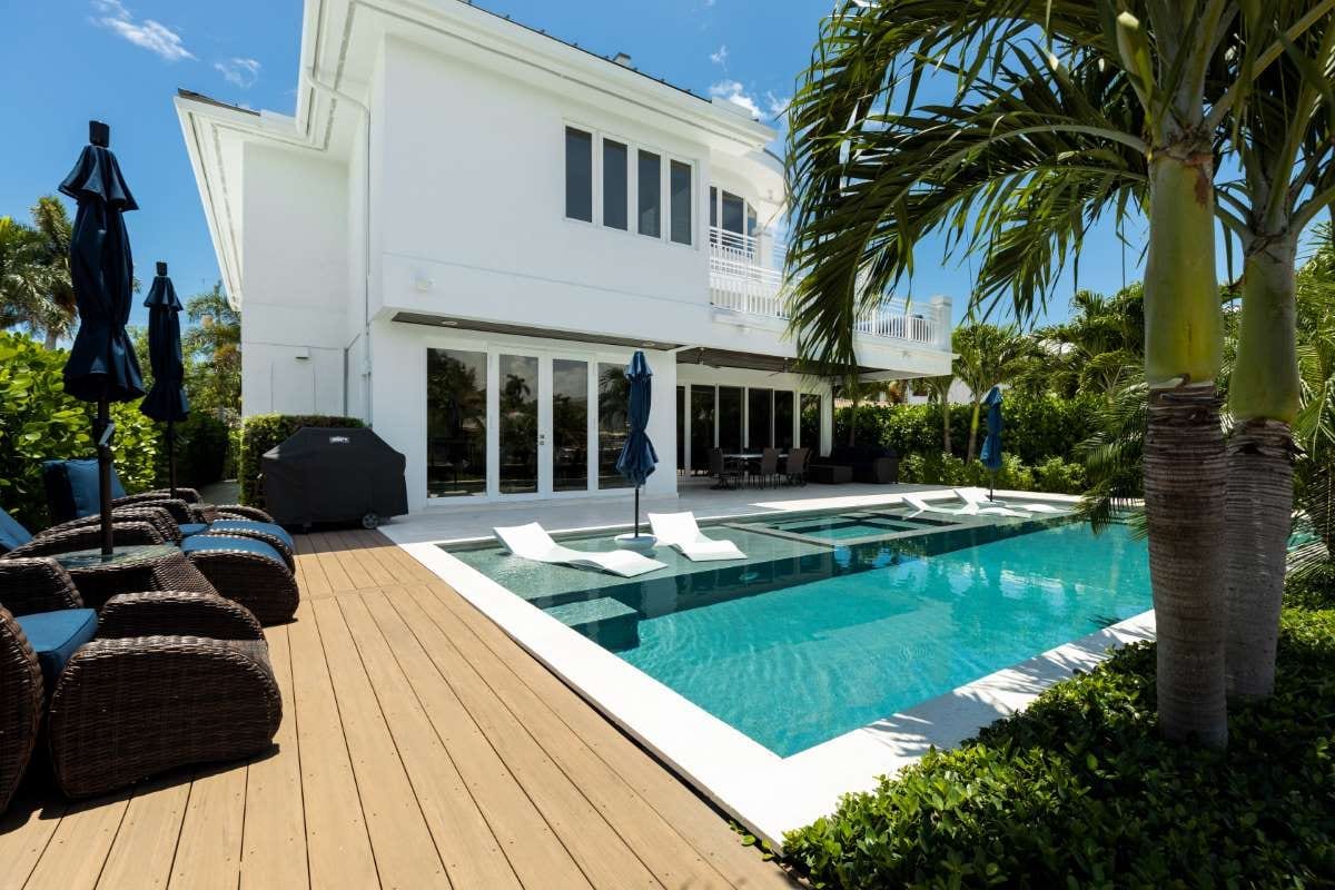 Modern backyard with swimming pool, artificial grass, stone path, trees, and chairs