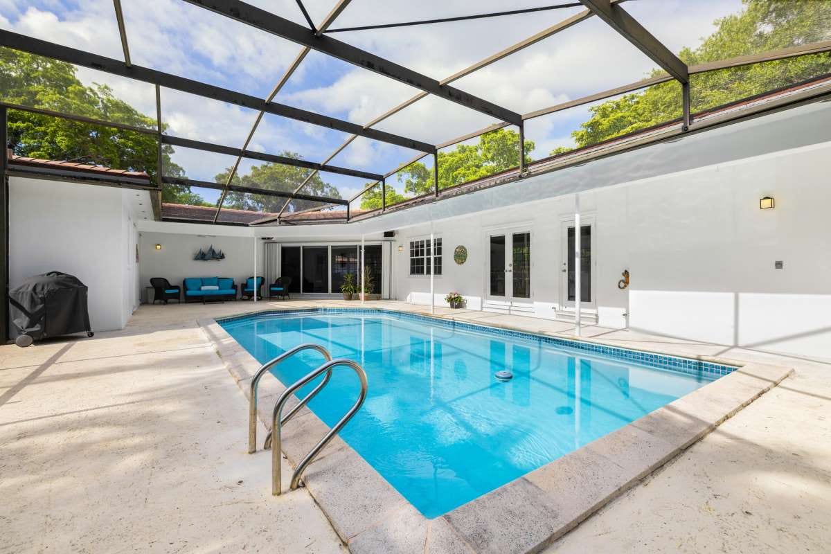 Backyard pool with landscaped patio and greenery