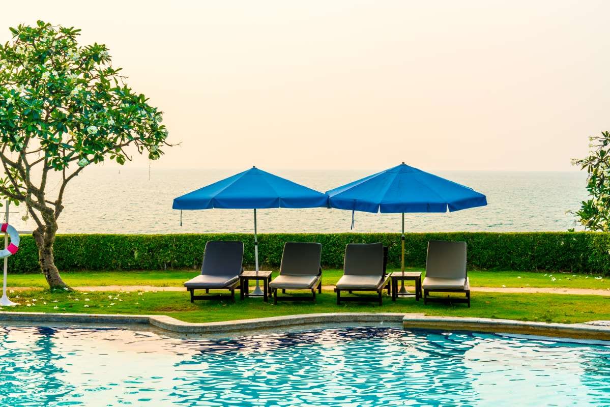 Beach chairs and umbrellas by a swimming pool at sunset with sea views