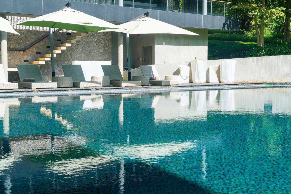 Poolside lounge chairs and umbrellas by a swimming pool at a holiday resort
