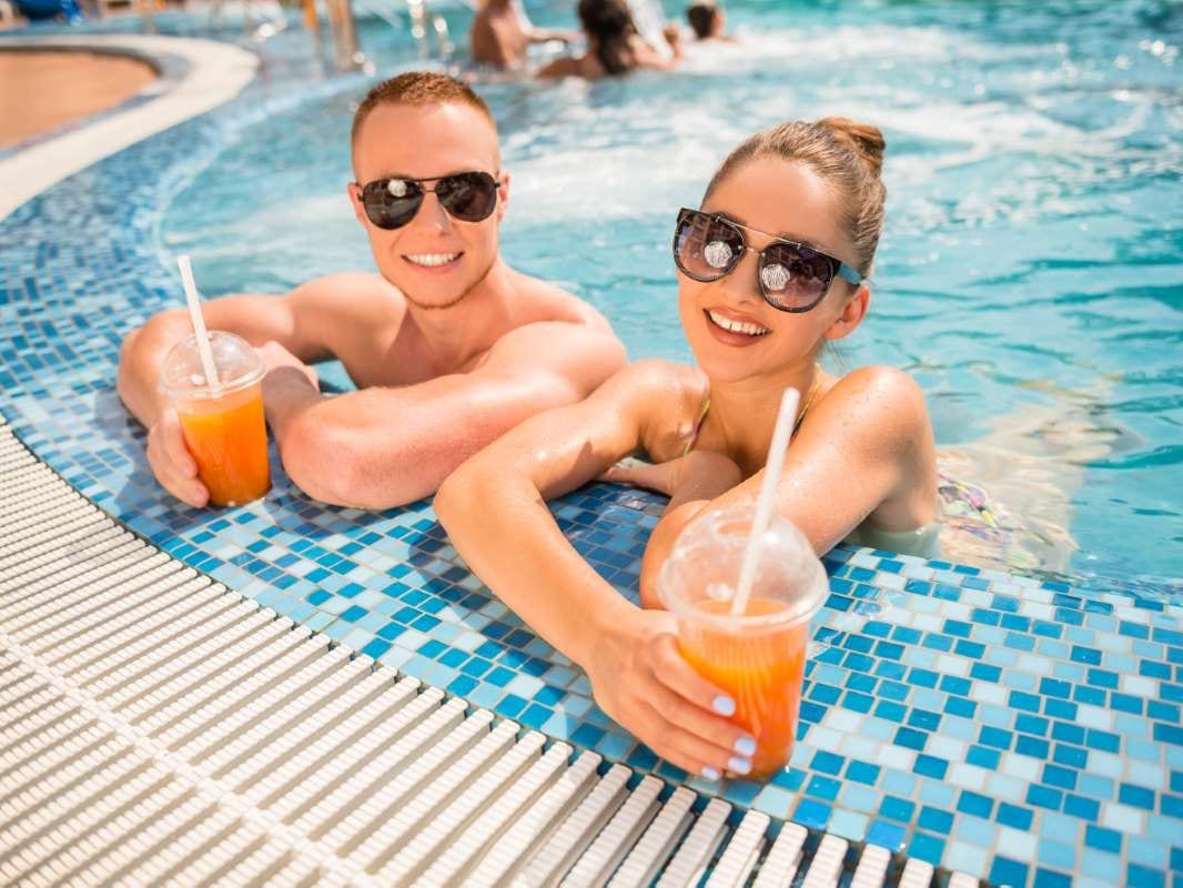 Couple relaxing by a resort swimming pool with cocktails