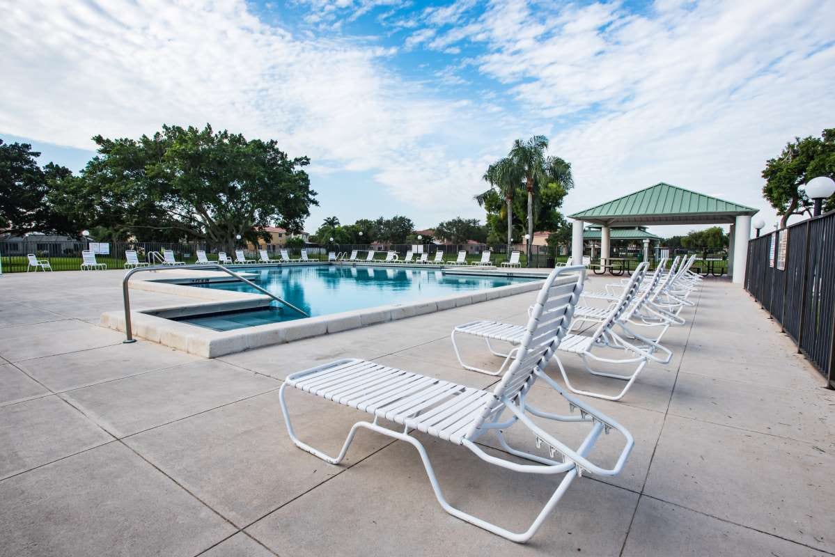 Empty chairs by a swimming pool under a clear sky