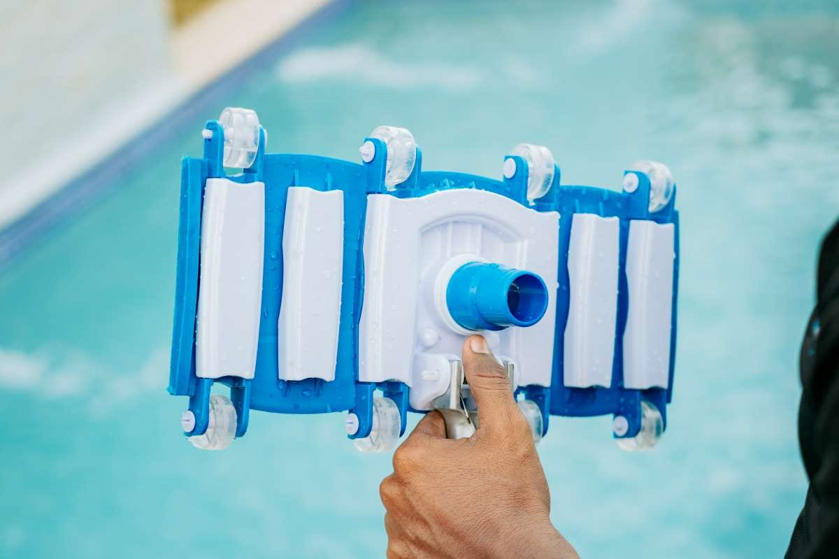 Hand holding a swimming pool sweeper head for pool cleaning and filtration
