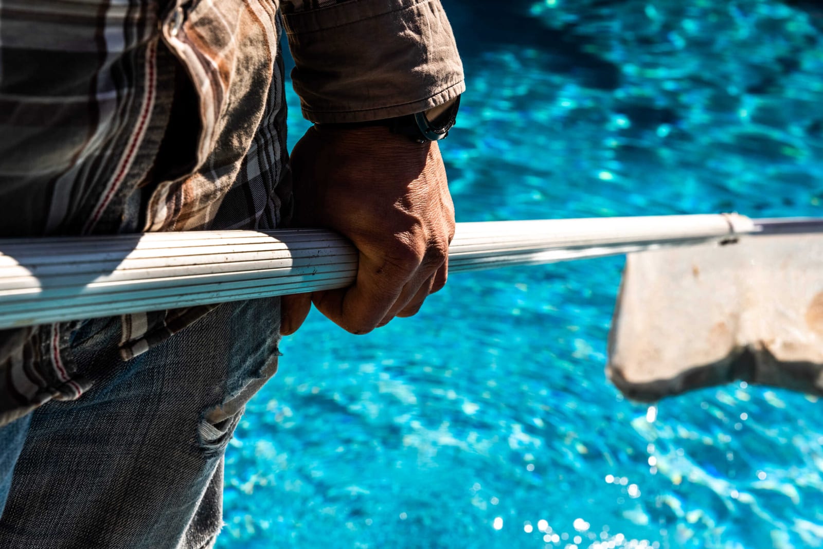Man holding pool netting beside a swimming pool