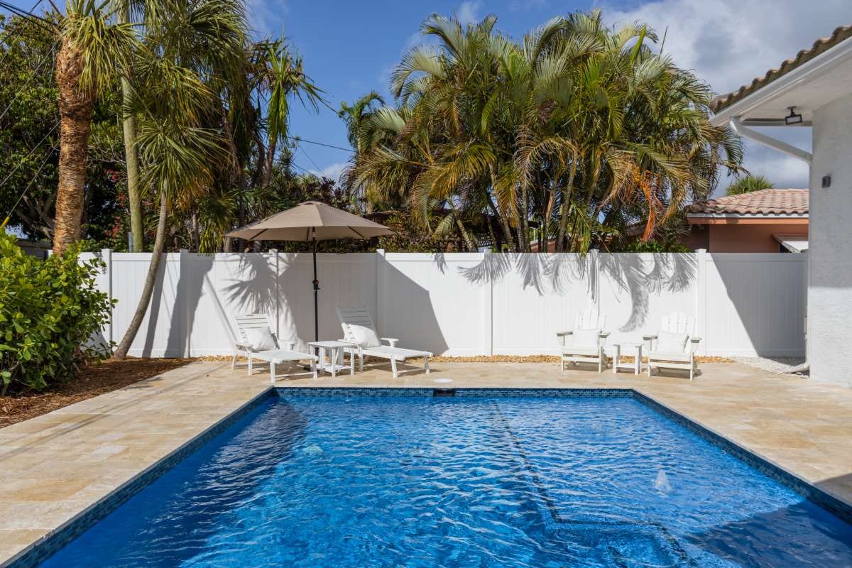 Modern building with swimming pool, trees, chairs, and blue sky landscape