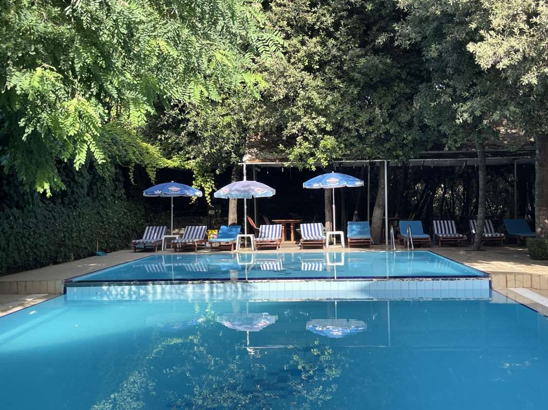 Pool with blue water, umbrellas, and chairs by the deck