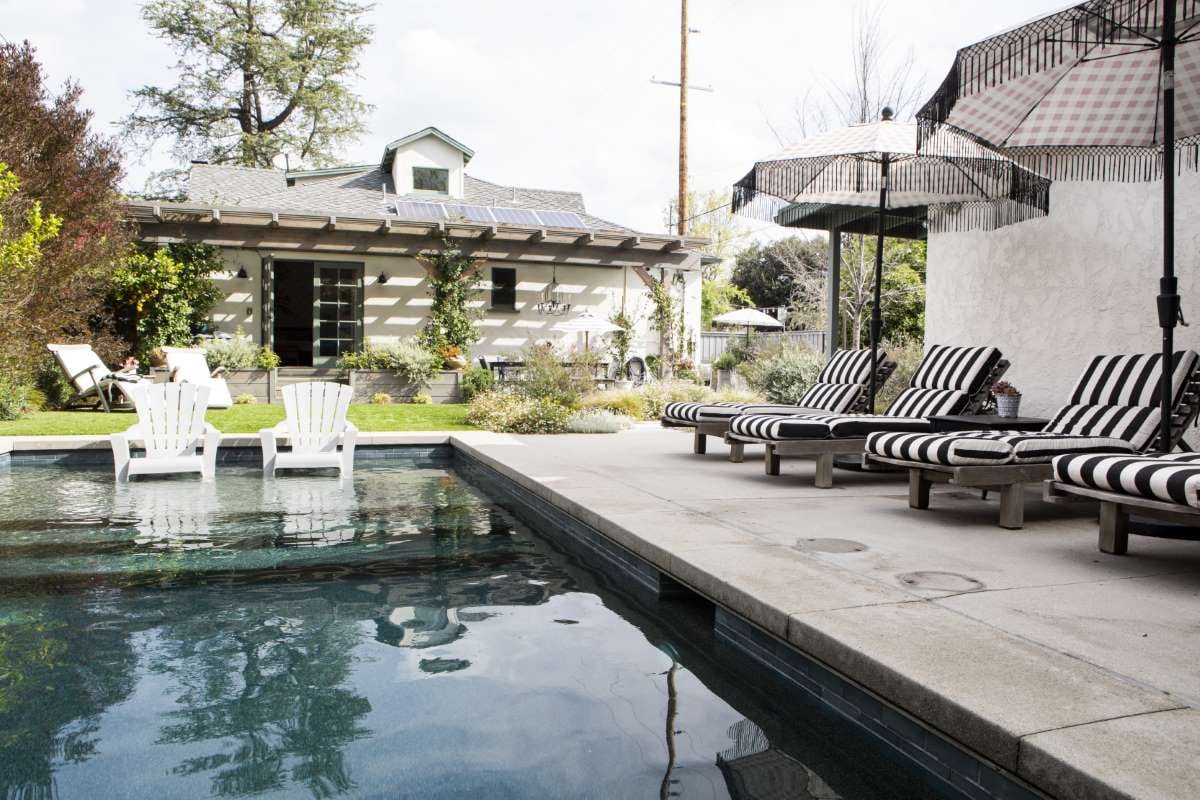 Wooden seats by a pool with parasols, suggesting a relaxed poolside service setting